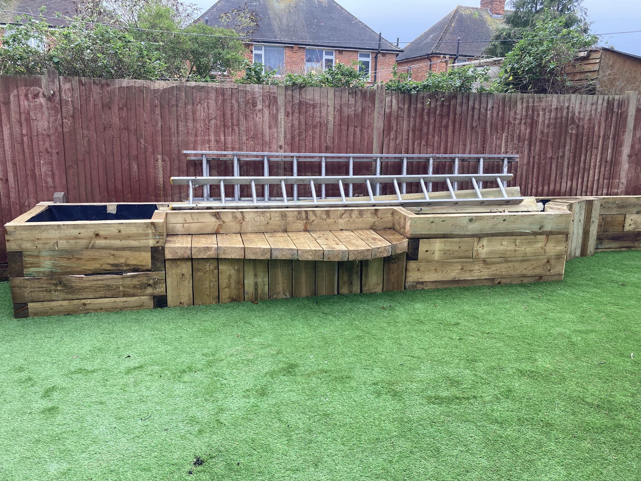 Sleeper planters and a built-in sleeper bench beside an artificial lawn