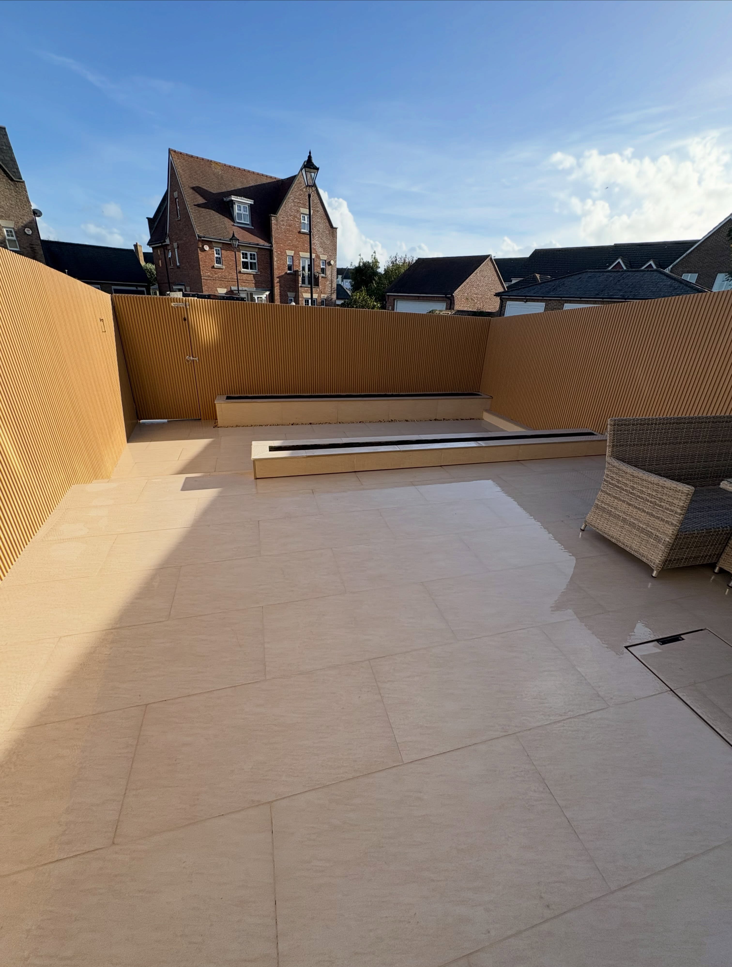 Large cream porcelain terrace with a raised planter and timber fencing